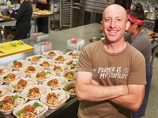 Kris Schlesser of community borrower LuckyBolt stands in front of prepared lunches