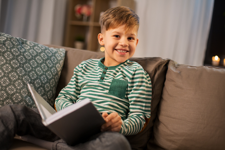 A happy child reading a book on the couch