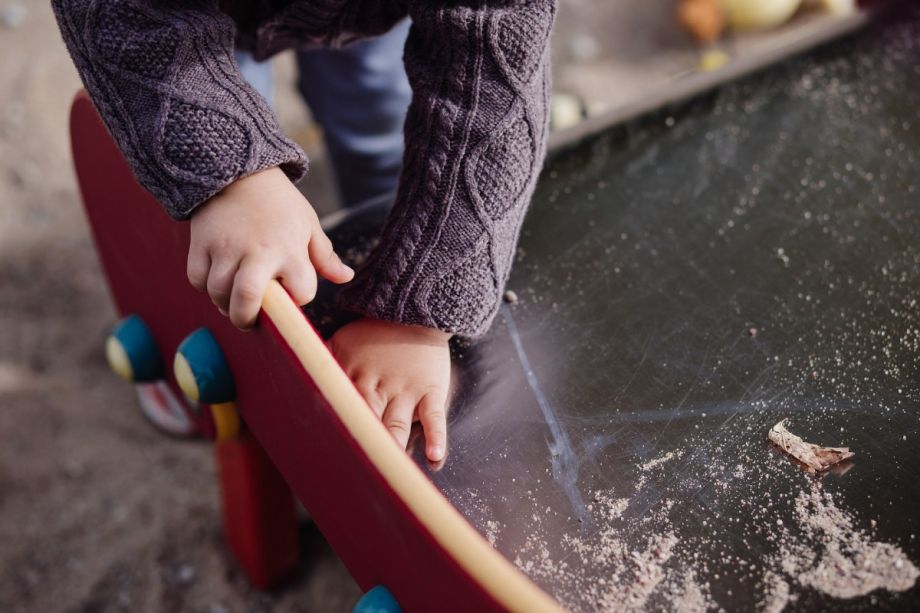 close up on a toddler's hands playing at a sand table