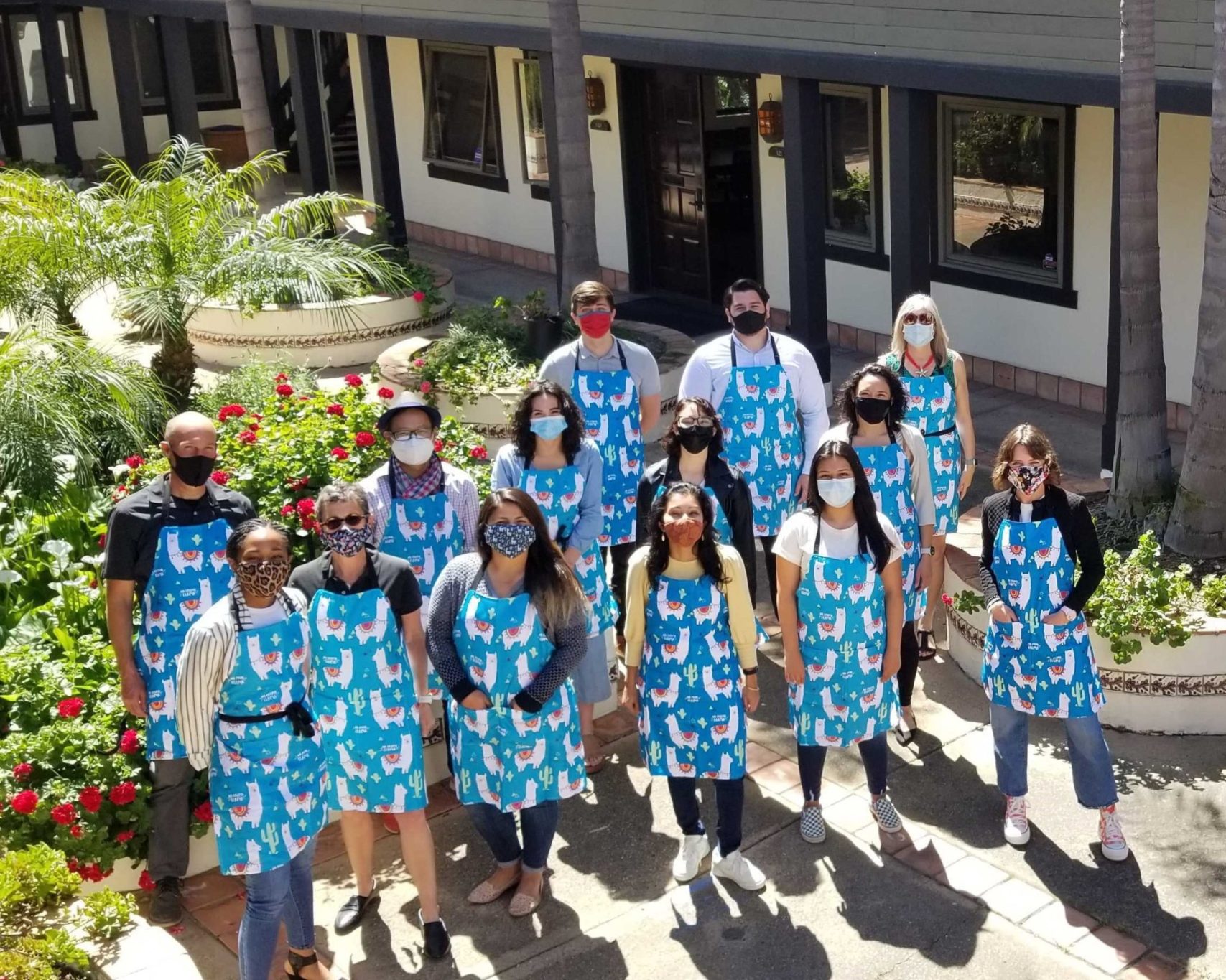 The Mission Driven Finance team standing in a courtyard wearing masks and matching aprons