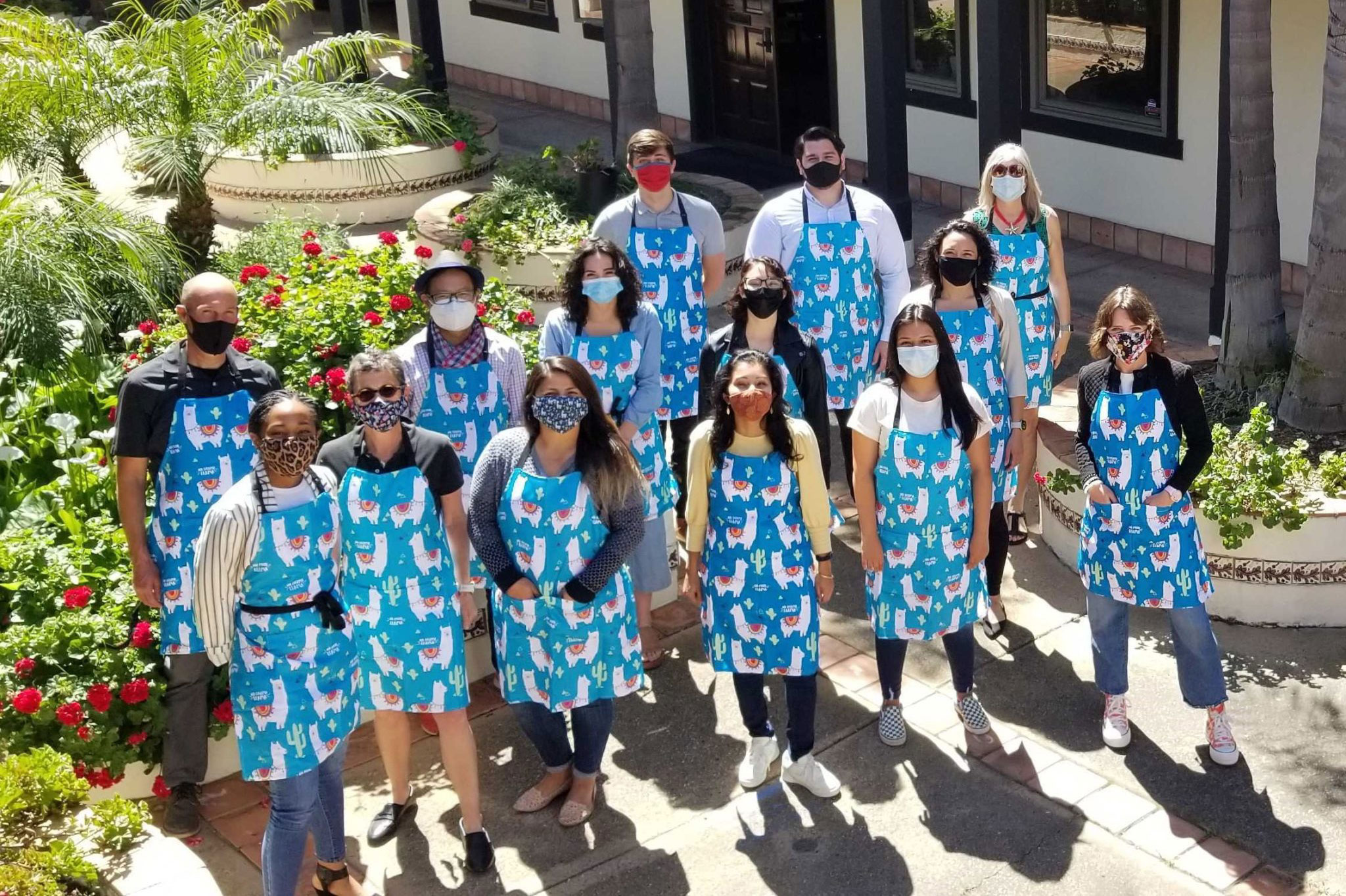 MDF-team-courtyard-aprons-3x2 The Mission Driven Finance team standing in a courtyard wearing matching aprons