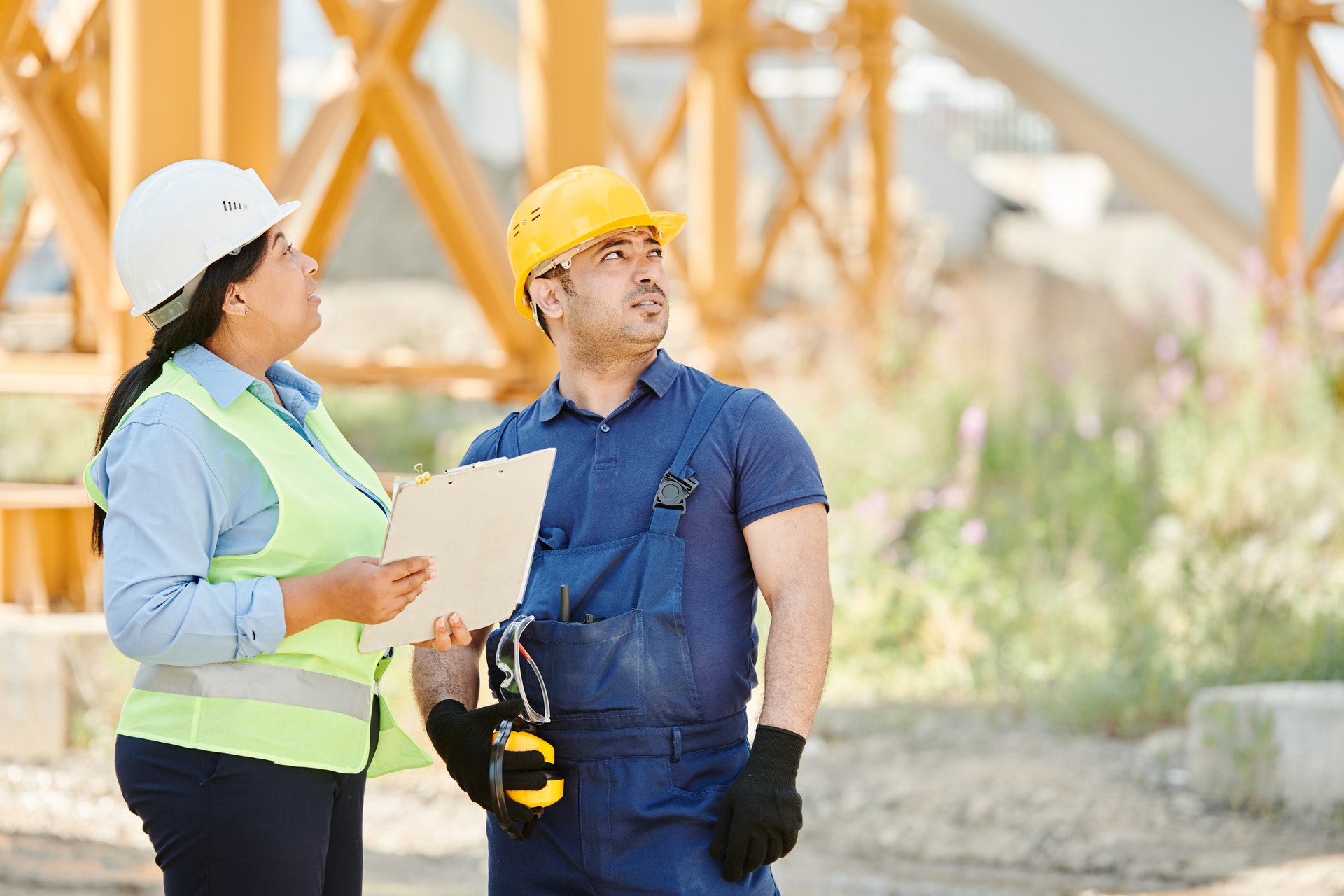 A woman and man wear protective clothing and hard hats at a construction site