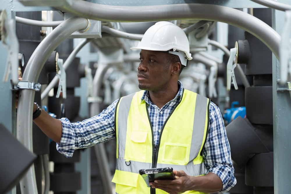 A man wearing a hard hat and a bright reflective vest looks pensively to the side