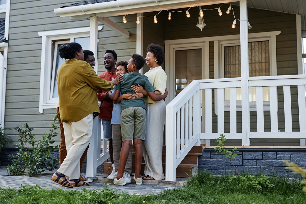 Stock image of a Black family hugging in front of a house