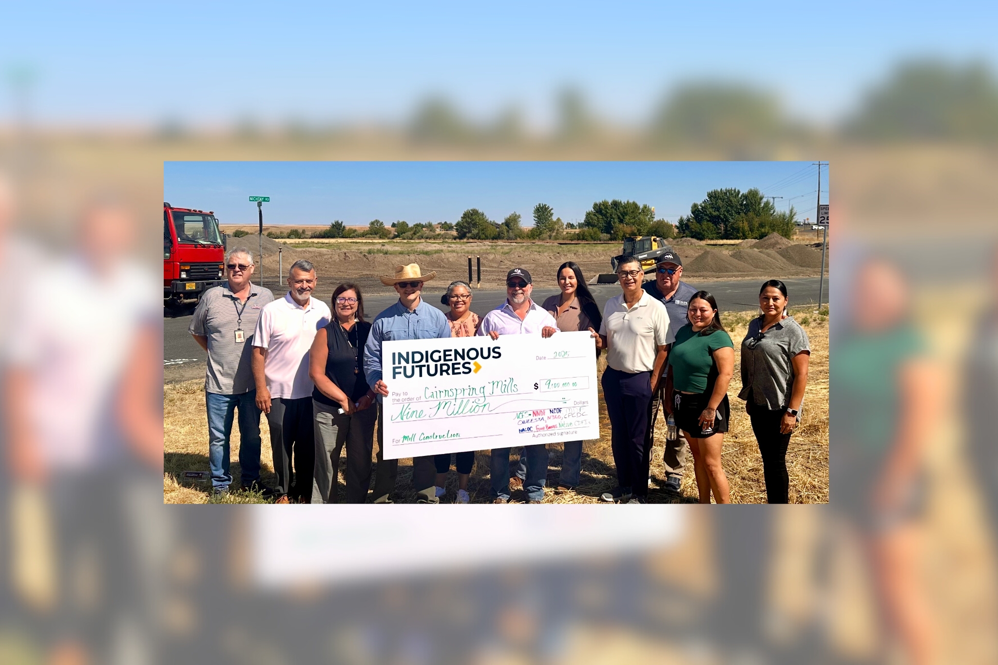 A group of people hold a giant check that says "Indigenous Futures" in the amount of "$9 million"